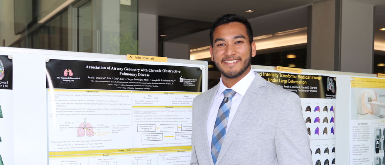 A researcher poses next to his poster