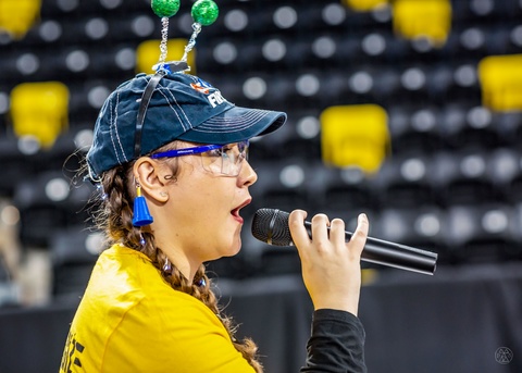 Alexa Christiansen speaks into a microphone at a FIRST comptetition 