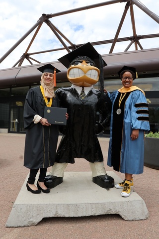 Harriet Nembhard and a student pose with Graduation Herky