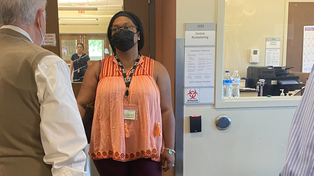 Woman wearing mask talks to two people in office