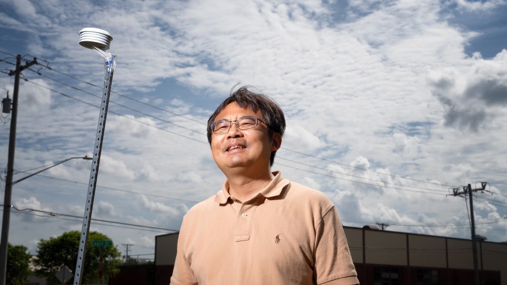 Jun Wang poses near a sensor outside